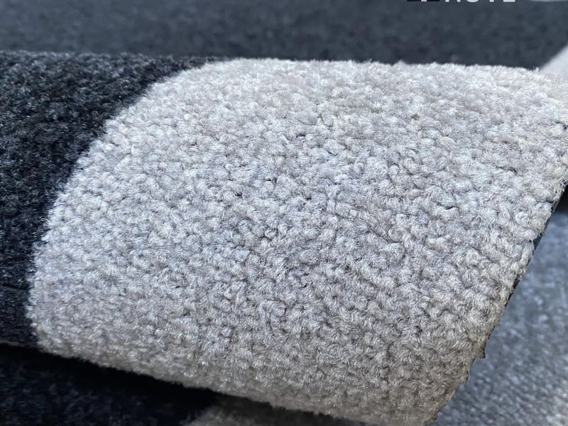 Detalhe da superfície têxtil de um tapete personalizado cinza enrolado