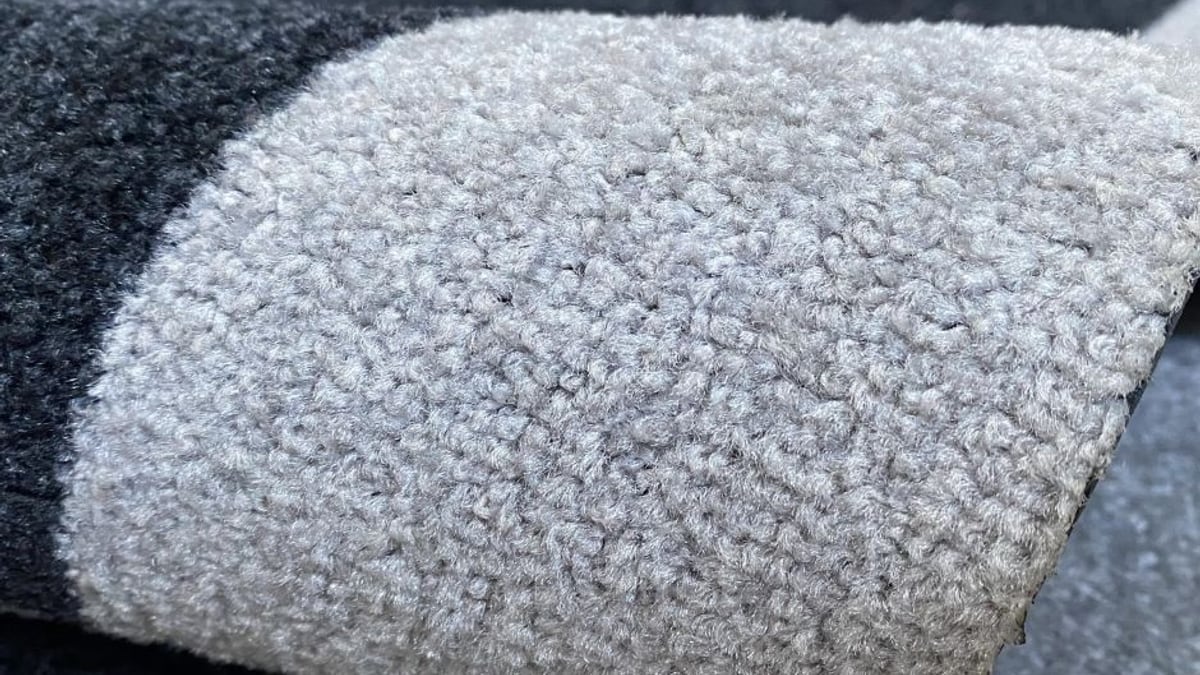 Detalhe da superfície têxtil de um tapete personalizado cinza enrolado Detalhe da superfície têxtil de um tapete personalizado cinza enrolado