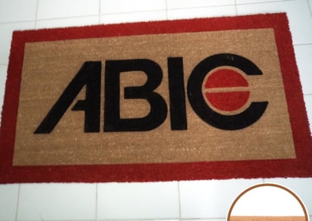 Capacho de fibra de coco com moldura vermelha e logotipo ABIC bordado