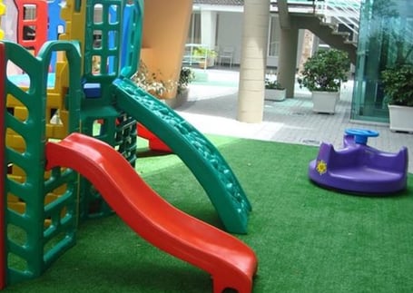 Grama sintética em playground com brinquedo e escorregador
