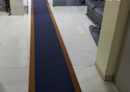 Passadeira emborrachada azul-marinho em corredor com piso de mármore