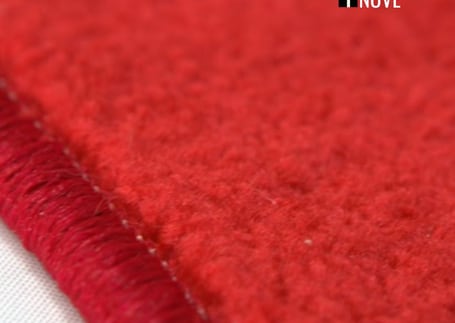 Detalhe do acabamento da borda de uma passadeira vermelha de carpete