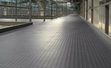 Piso emborrachado preto com padrão moeda em um corredor industrial
