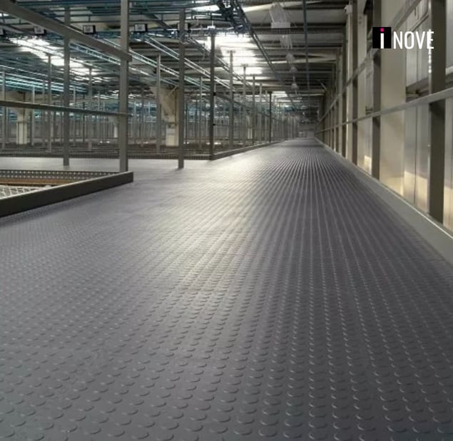 Piso emborrachado preto com padrão moeda em um corredor industrial