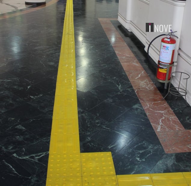 Piso tátil direcional amarelo sobre piso de mármore em um corredor Piso tátil direcional amarelo sobre piso de mármore em um corredor
