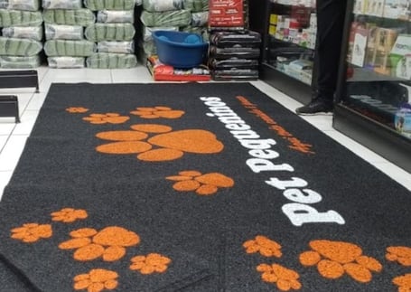 Tapete escuro de pet shop com patinhas laranja