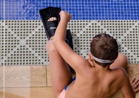 Nadador sentado sobre piso modular Acquakap azul à beira da piscina