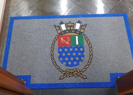 Tapete cinza com borda azul e brasão naval bordado Tapete cinza com borda azul e brasão naval bordado