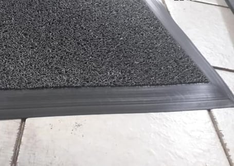 Tapete cinza com moldura de perfil preto sobre piso de cerâmica
