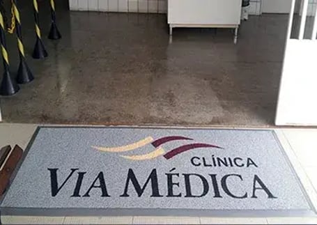 Tapete emborrachado cinza com logo de clínica médica na entrada
