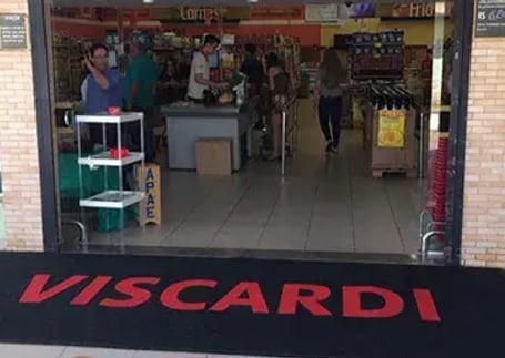 Tapete emborrachado preto com logo vermelho na entrada de supermercado