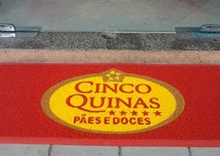 Tapete emborrachado vermelho com logo redondo na entrada de padaria
