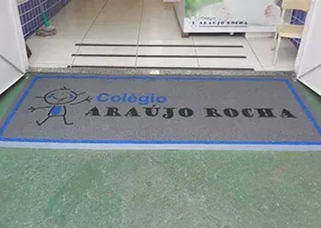 Tapete emborrachado cinza com borda azul na entrada de colégio
