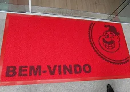 Tapete emborrachado vermelho de boas-vindas com mascote na entrada de restaurante