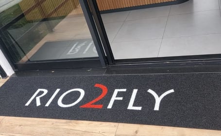 Tapete escuro da Rio2Fly na entrada da loja Tapete escuro da Rio2Fly na entrada da loja